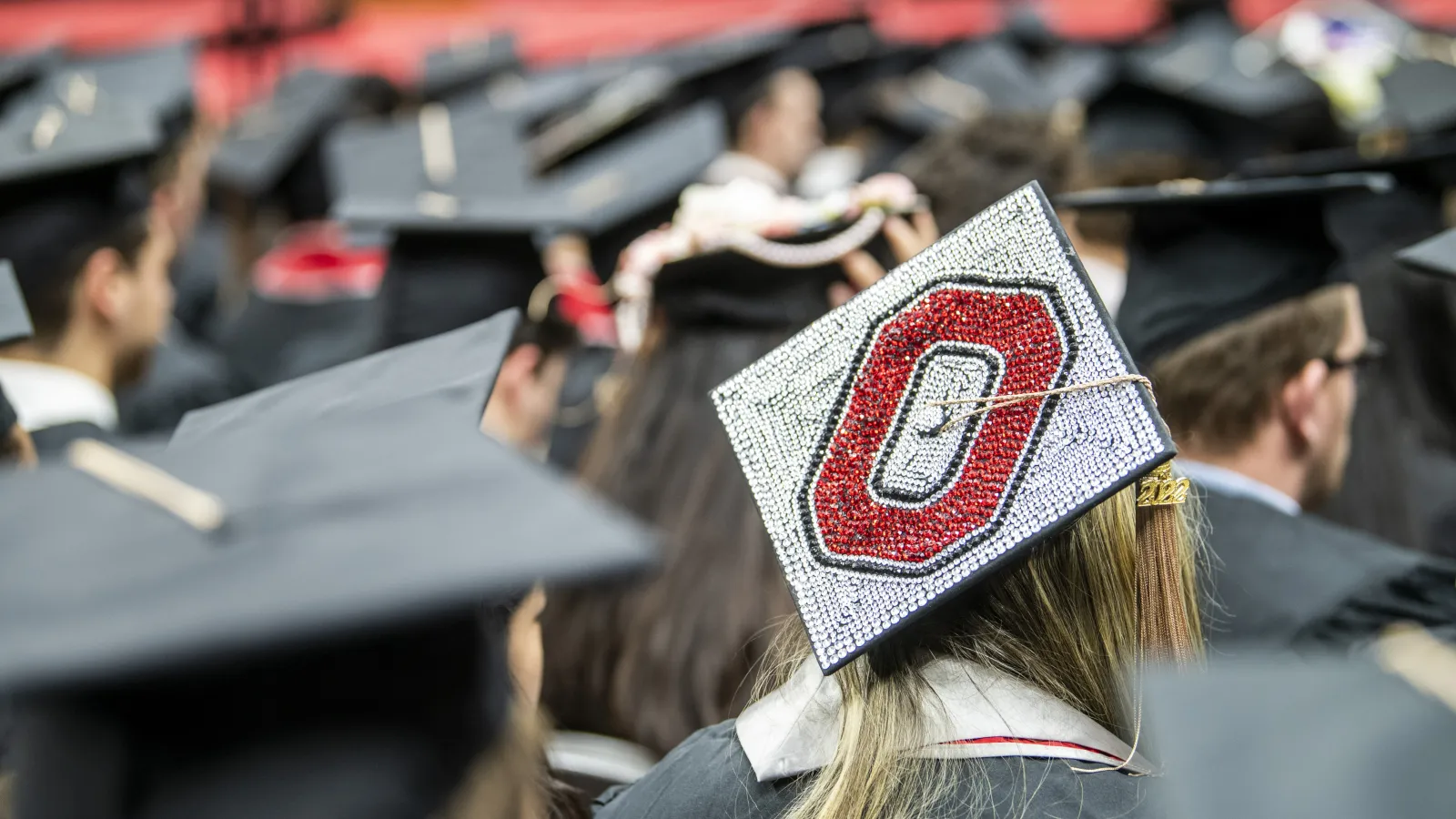back of graduation caps with one student's cap decorated with a scarlet block O and gray background