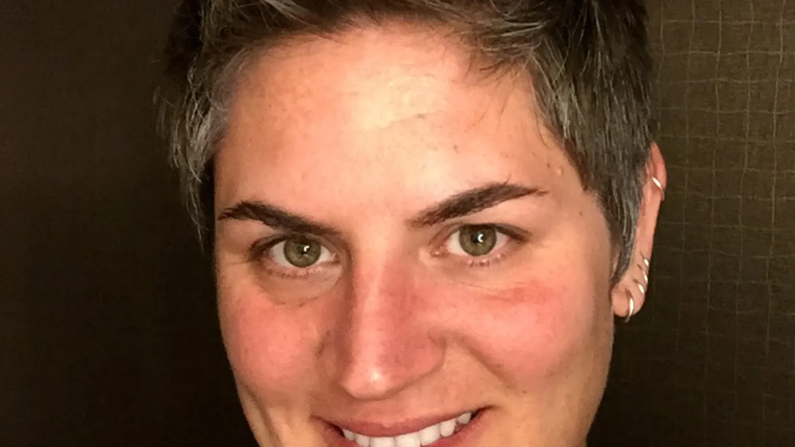 White female professor, turned toward camera smiling, wearing a black shirt.