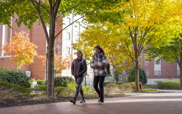 two students walking across campus in Autumn