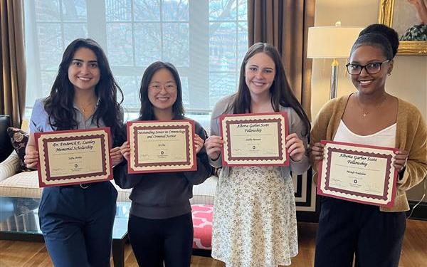 four undergraduate scholarship recipients holding their certificates