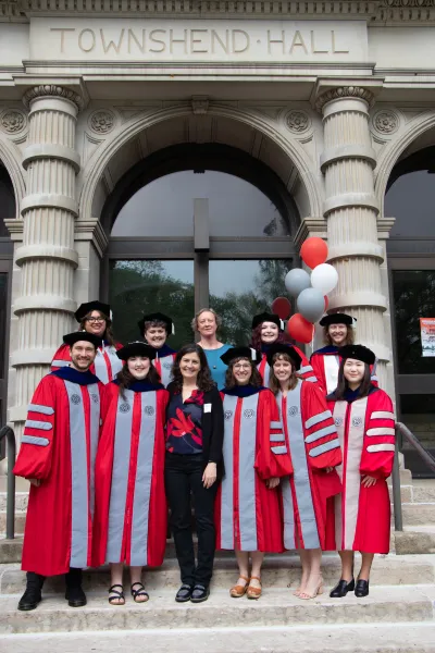 Spring 2025 PhD Recipients, wearing their formal regalia, in front of Townshend Hall with Professors Sarah Hayford and Rachel Dwyer