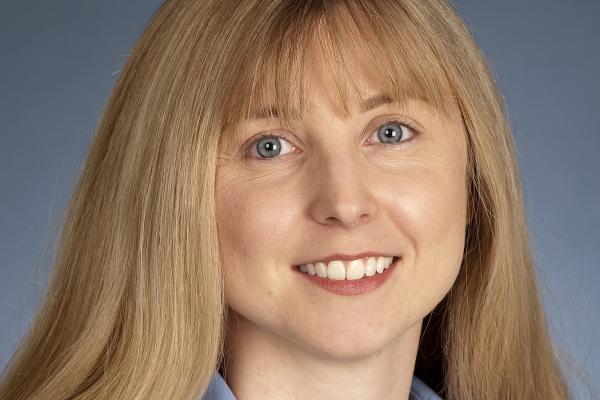 Image of white woman with blond hair, wearing a blue blouse smiling at the camera