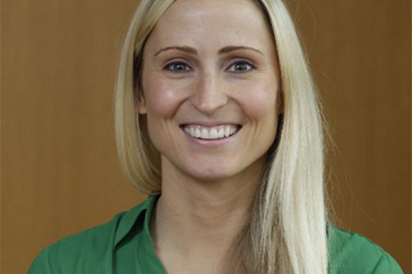 Image of white woman with blond hair, wearing a green blouse smiling at the camera