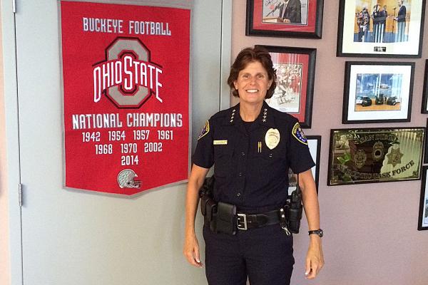 White female police officer standing by OSU memorabilia 