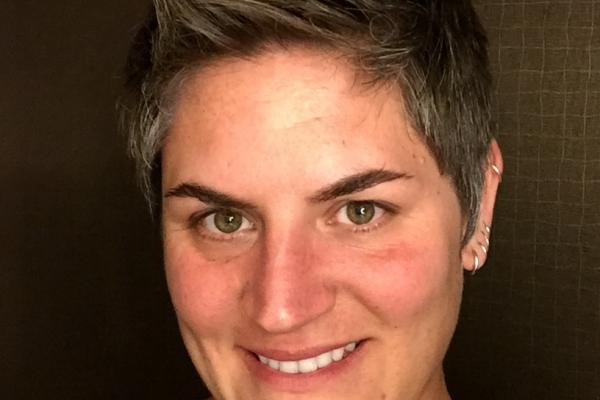 White female professor, turned toward camera smiling, wearing a black shirt.