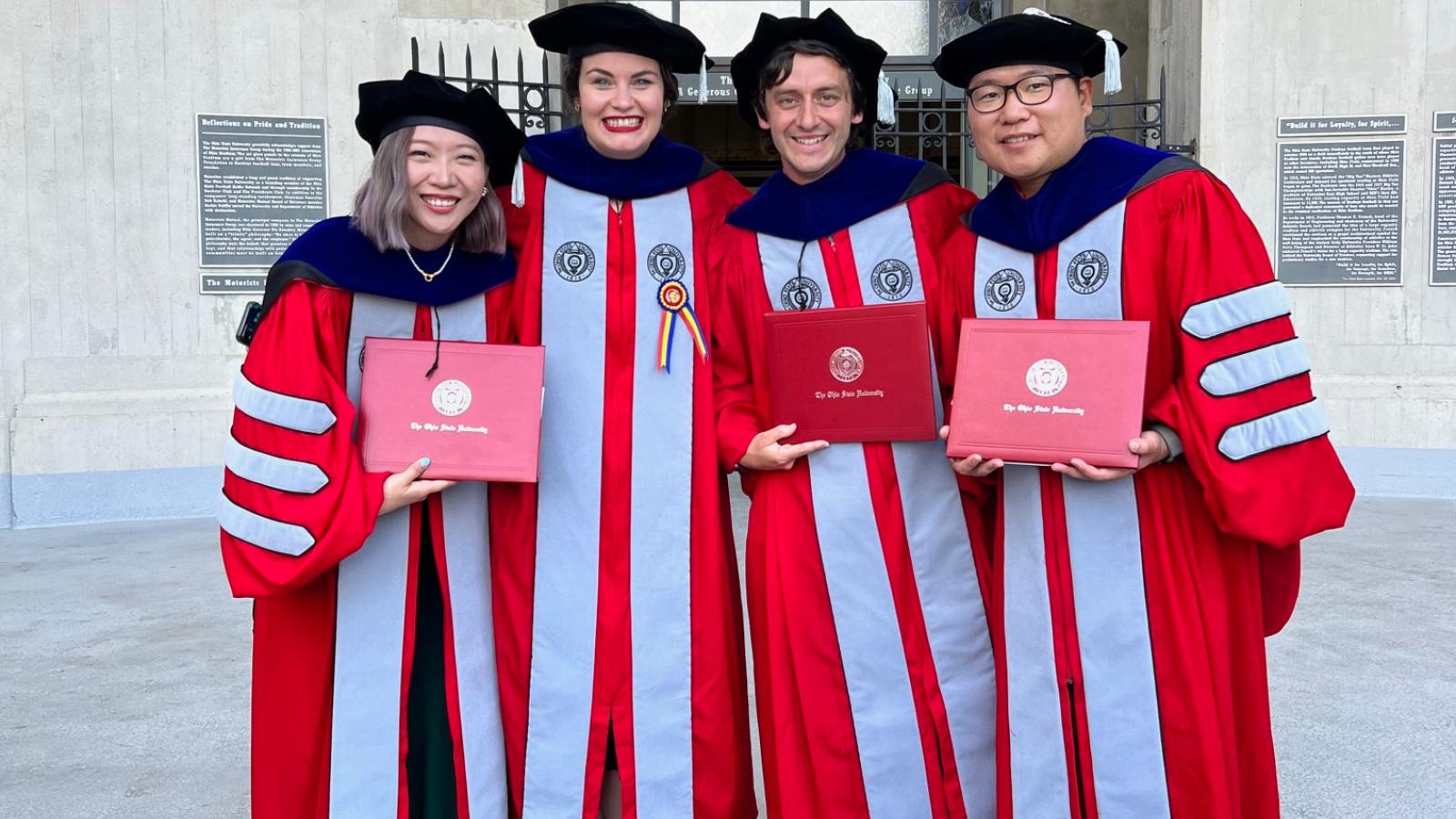Spring 2023 PhD graduates holding their diplomas