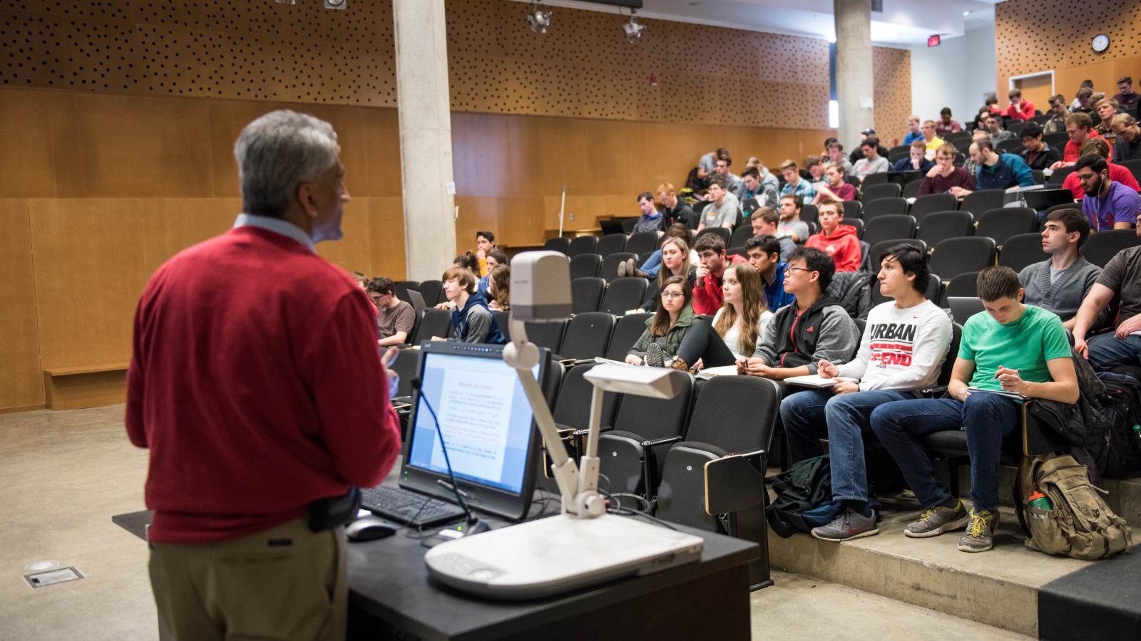 Professor standing in front of lecture hall full of students